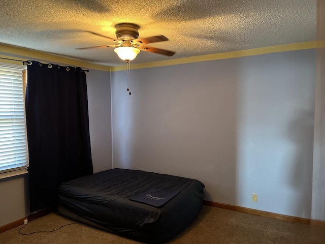 carpeted bedroom with ceiling fan and a textured ceiling