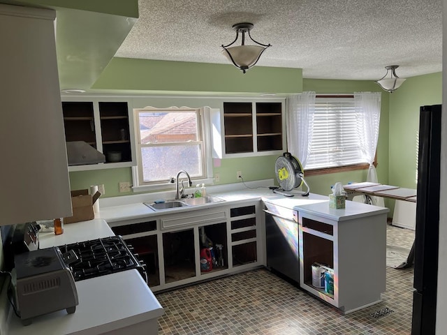 kitchen with black refrigerator, sink, light tile patterned floors, a textured ceiling, and kitchen peninsula