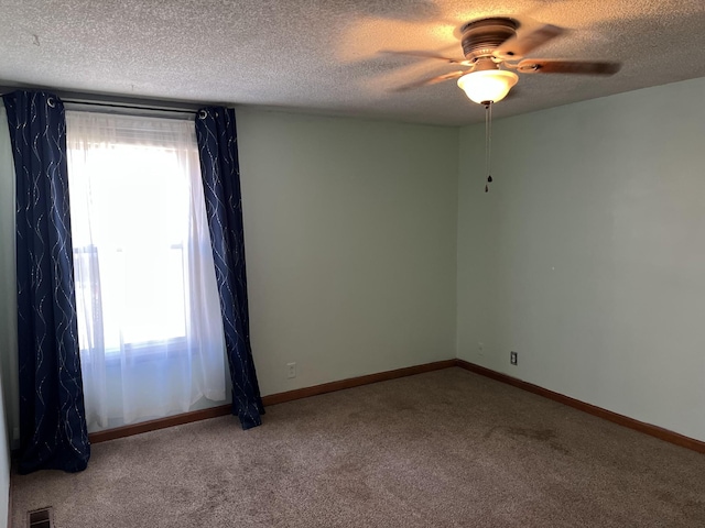 carpeted spare room with ceiling fan and a textured ceiling