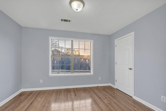 unfurnished room with a textured ceiling and hardwood / wood-style flooring