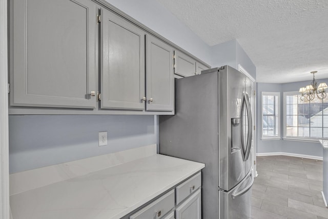 kitchen featuring a chandelier, stainless steel fridge with ice dispenser, hanging light fixtures, and gray cabinetry