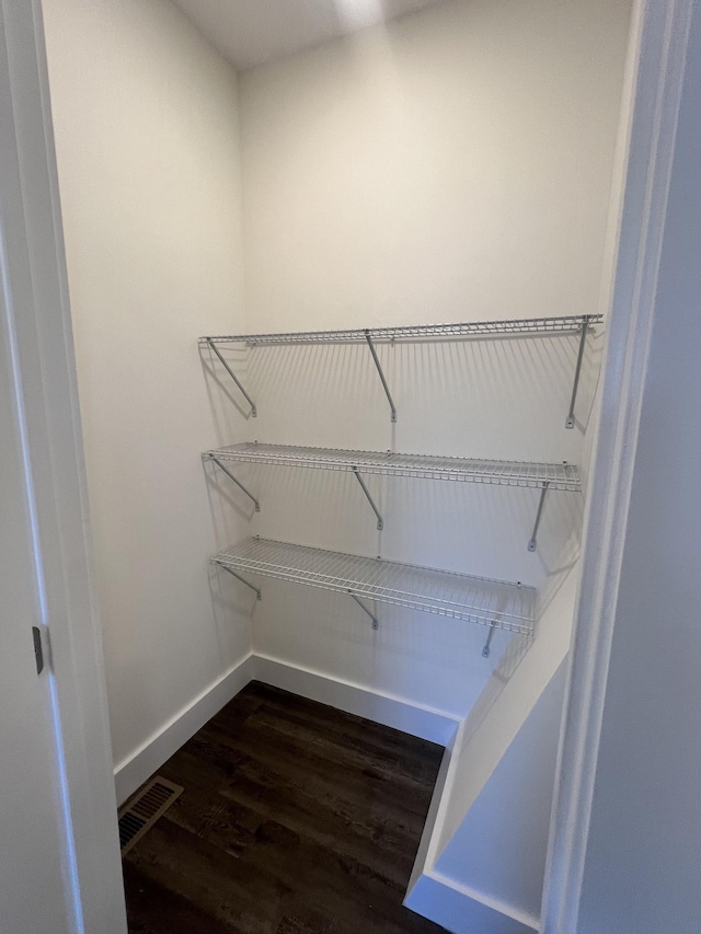 walk in closet with dark hardwood / wood-style flooring