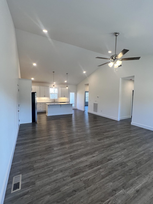 unfurnished living room featuring lofted ceiling, sink, dark hardwood / wood-style floors, and ceiling fan