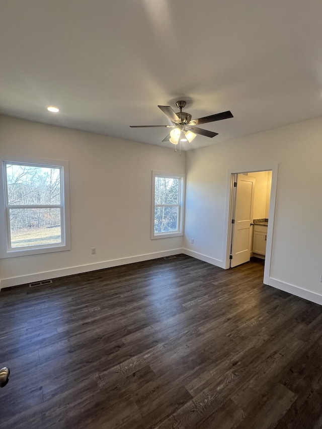 empty room with ceiling fan and dark hardwood / wood-style flooring