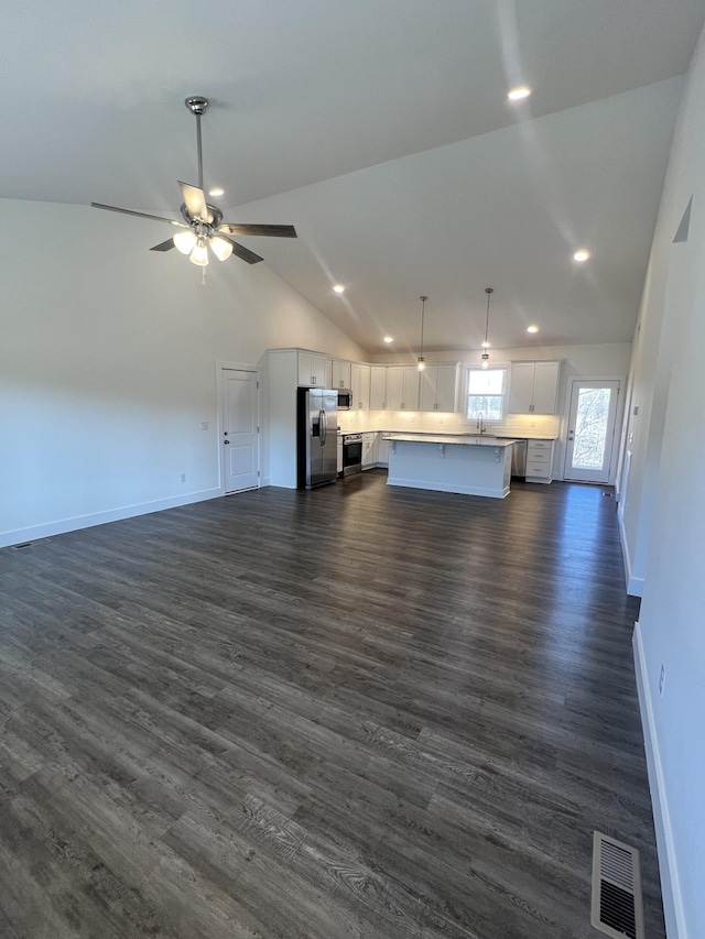 unfurnished living room with dark hardwood / wood-style flooring, high vaulted ceiling, and ceiling fan