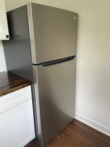 kitchen with stainless steel refrigerator, white cabinetry, dark hardwood / wood-style flooring, and wooden counters