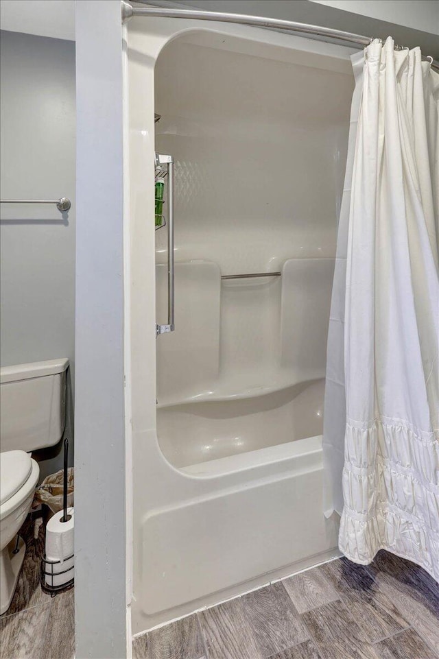 bathroom featuring shower / tub combo, hardwood / wood-style flooring, and toilet