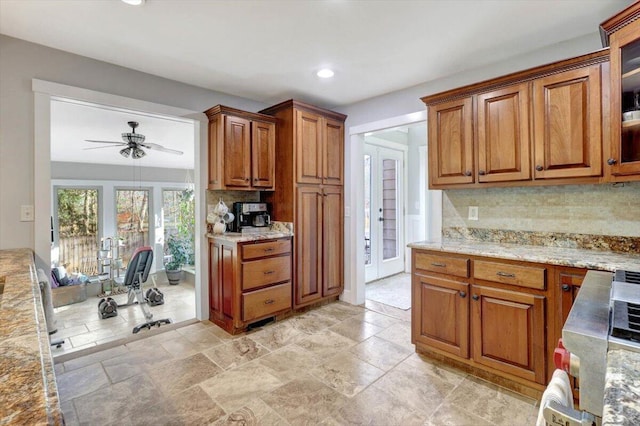 kitchen with ceiling fan, light stone counters, backsplash, and vaulted ceiling