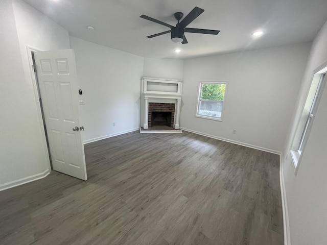 unfurnished living room featuring a fireplace, dark hardwood / wood-style floors, and ceiling fan