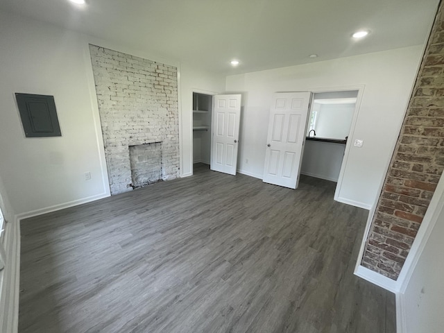 unfurnished living room with a fireplace, electric panel, and dark wood-type flooring