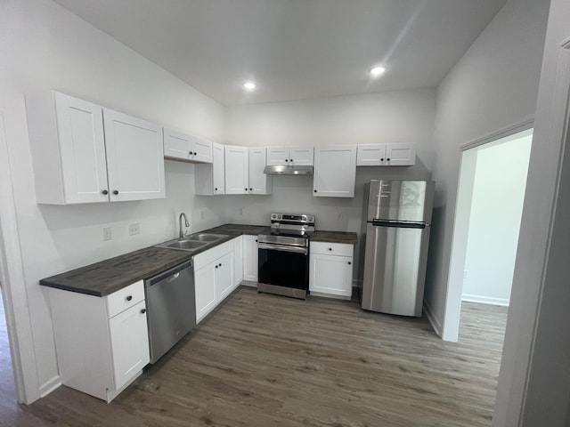 kitchen with appliances with stainless steel finishes, dark hardwood / wood-style flooring, white cabinetry, and sink