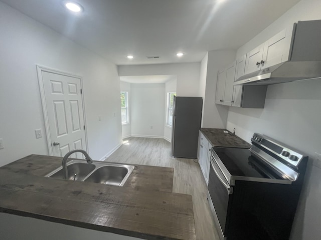 kitchen featuring appliances with stainless steel finishes, light wood-type flooring, extractor fan, sink, and white cabinets