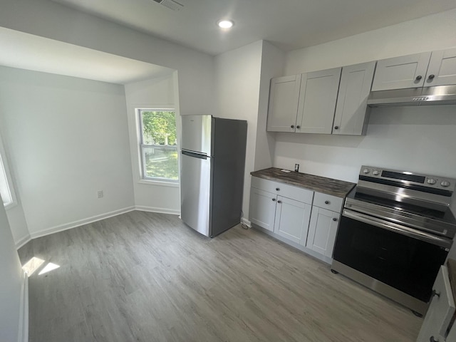 kitchen with wooden counters, light wood-type flooring, and appliances with stainless steel finishes