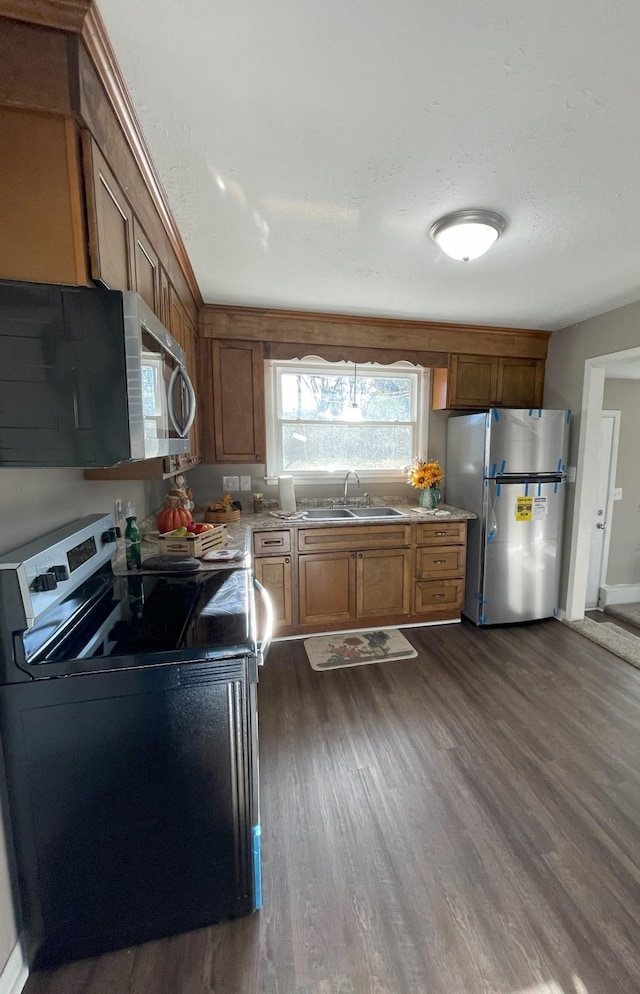 kitchen featuring light stone countertops, sink, appliances with stainless steel finishes, and dark wood-type flooring