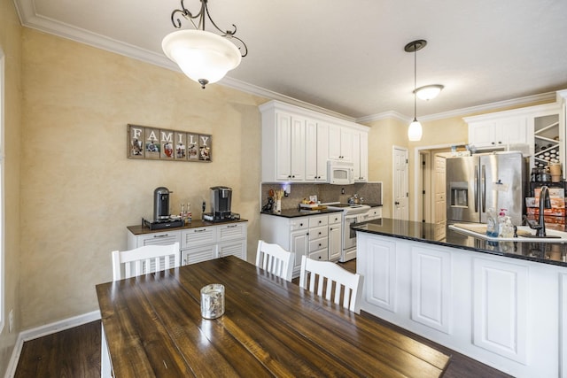 kitchen featuring white cabinetry, sink, dark hardwood / wood-style flooring, decorative light fixtures, and white appliances