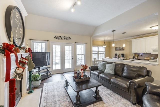 living room featuring rail lighting, vaulted ceiling, a textured ceiling, and light hardwood / wood-style flooring