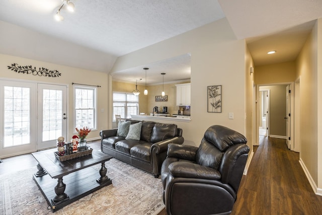 living room featuring lofted ceiling, sink, wood-type flooring, and a textured ceiling