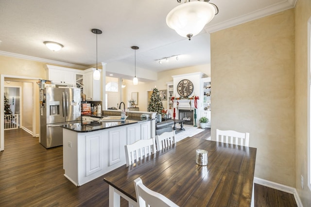 dining room with sink, rail lighting, dark hardwood / wood-style floors, and ornamental molding