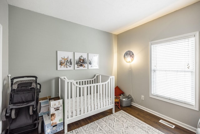 bedroom featuring dark hardwood / wood-style floors and a crib