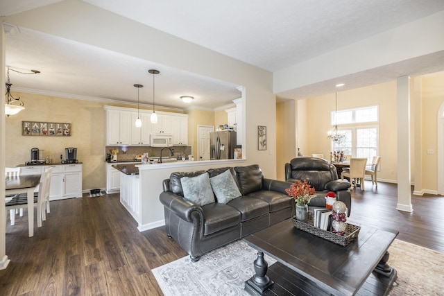 living room with dark hardwood / wood-style flooring, crown molding, a notable chandelier, and sink