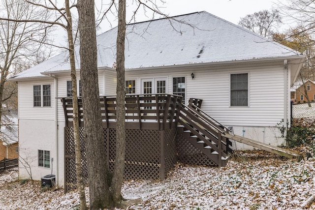 snow covered house with a deck and central air condition unit