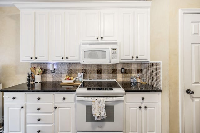 kitchen featuring tasteful backsplash, white cabinetry, dark stone counters, and white appliances