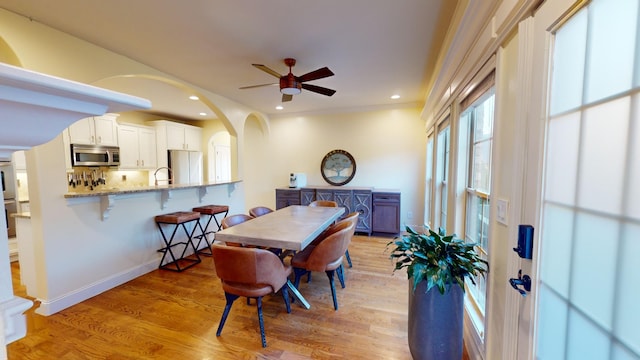 dining space with ceiling fan, light hardwood / wood-style flooring, ornamental molding, and sink