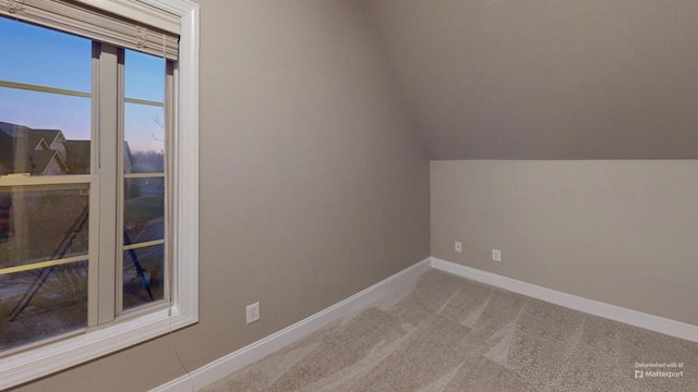 carpeted spare room with vaulted ceiling