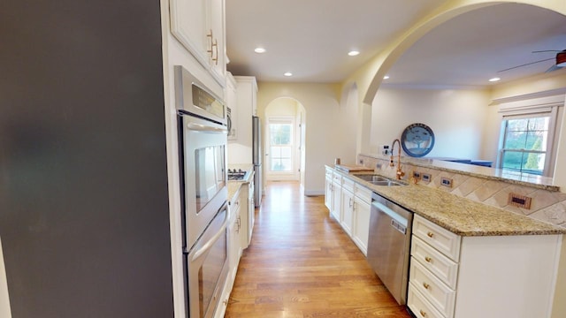 kitchen featuring light stone countertops, backsplash, stainless steel dishwasher, sink, and white cabinets