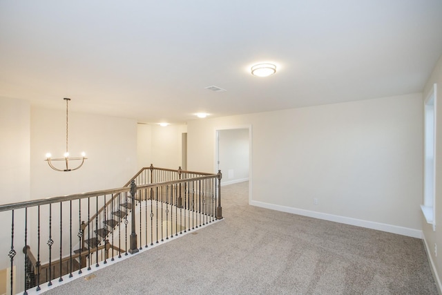 carpeted empty room featuring an inviting chandelier