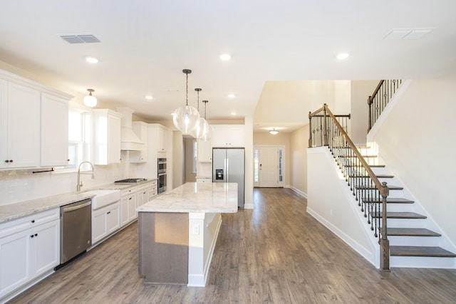 kitchen featuring decorative light fixtures, a center island, white cabinetry, and appliances with stainless steel finishes