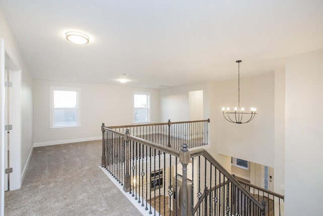 corridor with carpet flooring and a chandelier