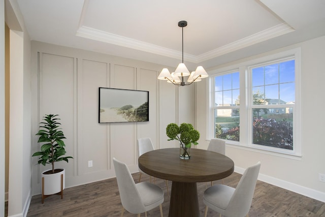 dining area with a chandelier, dark hardwood / wood-style flooring, a tray ceiling, and ornamental molding