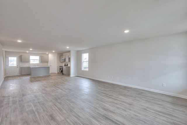 unfurnished living room featuring light hardwood / wood-style floors and sink