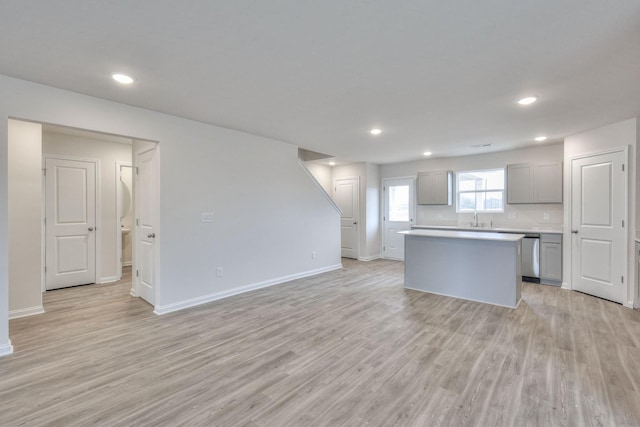 kitchen featuring gray cabinetry, dishwasher, sink, light hardwood / wood-style floors, and a kitchen island