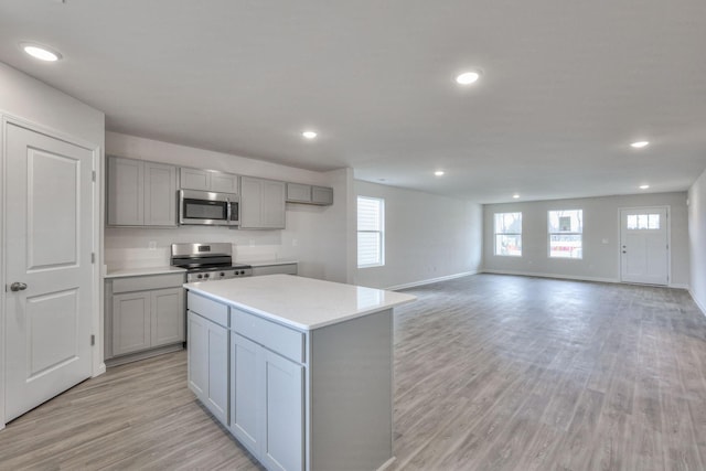 kitchen with gray cabinetry, a center island, appliances with stainless steel finishes, and light hardwood / wood-style flooring