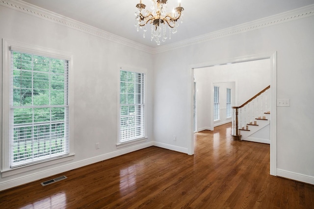 spare room with a healthy amount of sunlight, crown molding, dark wood-type flooring, and a chandelier