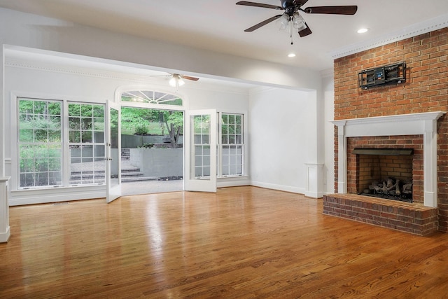 unfurnished living room featuring a fireplace, hardwood / wood-style flooring, ceiling fan, and ornamental molding