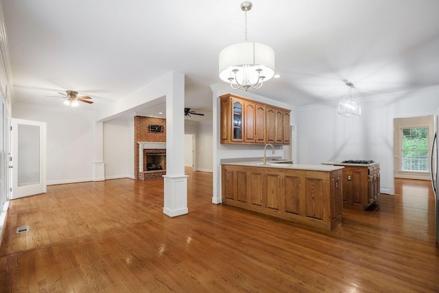 kitchen with kitchen peninsula, crown molding, hardwood / wood-style floors, and hanging light fixtures