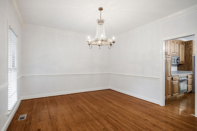 unfurnished dining area with dark hardwood / wood-style floors, ornamental molding, and an inviting chandelier