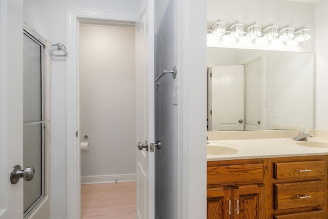 bathroom with hardwood / wood-style flooring, vanity, and shower / bath combination with glass door