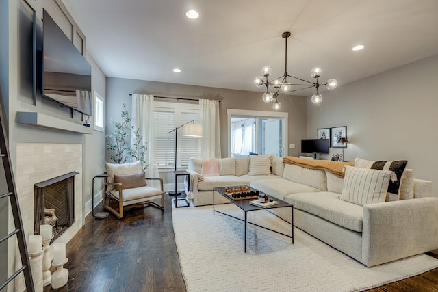 living room with a fireplace, plenty of natural light, dark hardwood / wood-style floors, and a notable chandelier