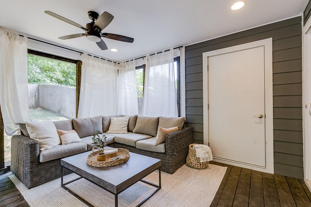 living room featuring hardwood / wood-style flooring, ceiling fan, and wood walls