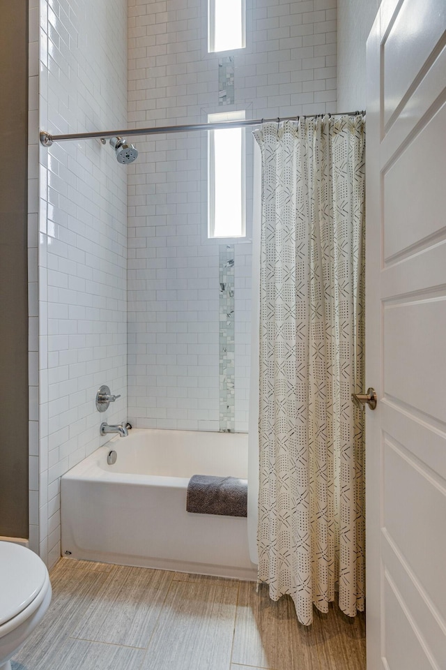 bathroom with shower / bath combination with curtain, hardwood / wood-style flooring, and toilet