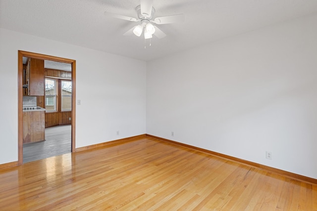 empty room featuring ceiling fan, light wood-type flooring, and a textured ceiling