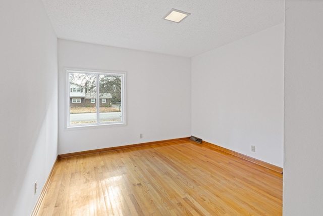 empty room with a textured ceiling and hardwood / wood-style flooring