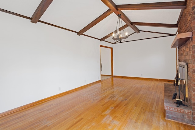 unfurnished living room with vaulted ceiling with beams, a fireplace, an inviting chandelier, and hardwood / wood-style flooring