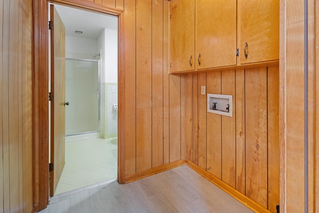 laundry room with wooden walls, hookup for a washing machine, cabinets, and light wood-type flooring