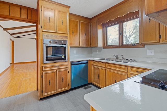 kitchen with a textured ceiling, sink, light wood-type flooring, and stainless steel appliances