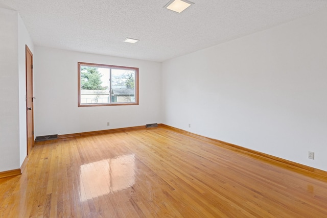 unfurnished room featuring light hardwood / wood-style flooring and a textured ceiling